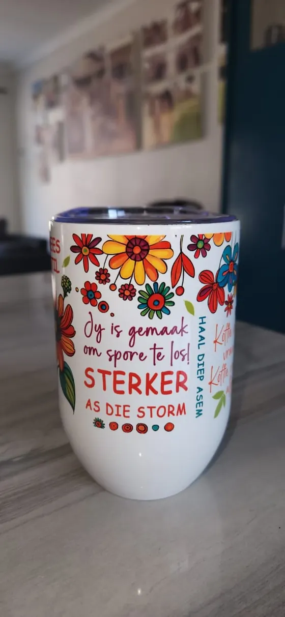 White gin tumbler printed in Afrikaans Jy is gemaak om spore te los, Sterker as die storm, with bright flowers