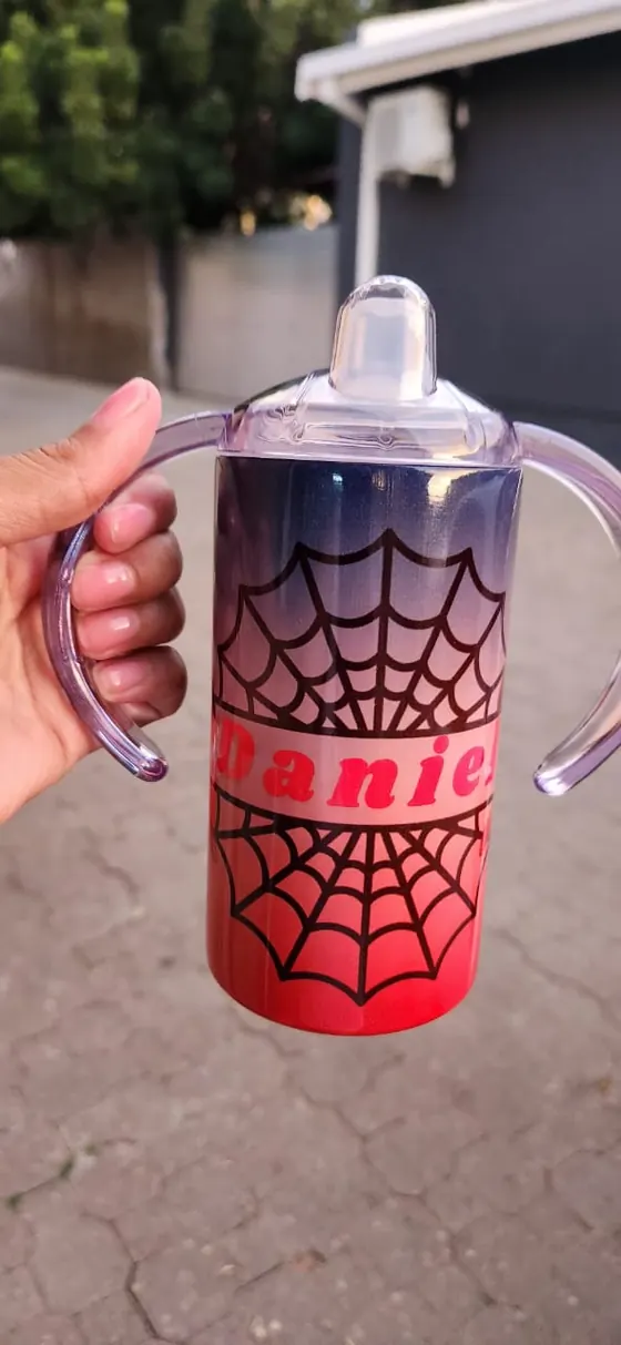 Kids sippy cup with two handles printed with a red spiderweb pattern and a name